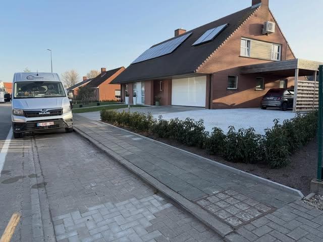 Afgewerkte oprit en voortuin bij een woning, uitgevoerd door Devooght Grond en Bouw
